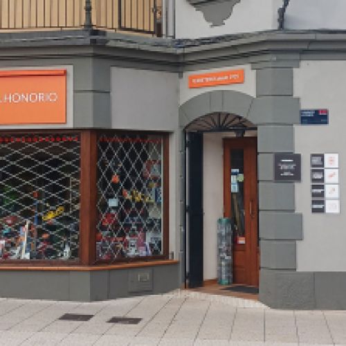 Exterir de la ferretería con fachada gris y letrero naranja